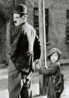 Photographie de Charlot l'air nerv tenant la main  un petit garon en haillons
